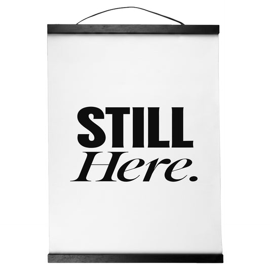 "Still Here." — Quorum Hanging Canvas, pure white type on Sign Black canvas with white hanger